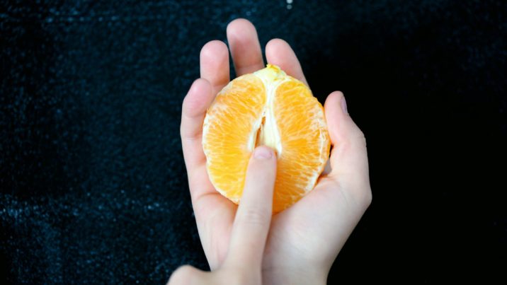 An image of a young person holding a ripe orange to show the similarity of the female genitalia.