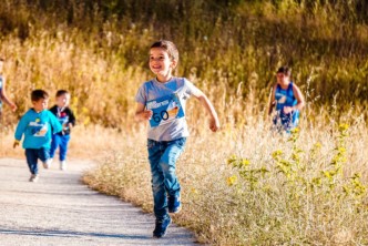 Lapset juoksevat iloisena pellon reunalla olevalla tiellä